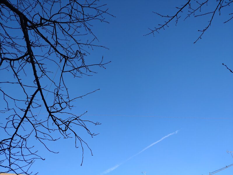 乾燥した冬の空に伸びる飛行機雲と青空。ウォーキングを始めた理由になった朝の空
